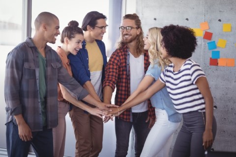 Cheerful business people stacking hands in creative